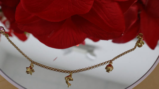Manilla para ninas con colgantes de un delfin , una concha ,una estrellita y dos piedrita en oro de 10k